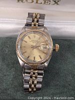 Front view of watch showing dial, bezel, bracelet and box interior