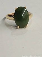 Top-down close-up of ring showing oval nephrite jade cabochon and gold band.