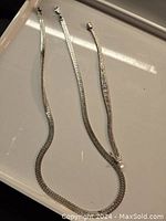 Full view of necklace and bracelet laid out on a white tray showing their overall length and design.