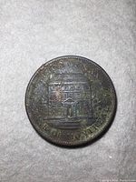 Photo of the obverse side of the antique 1842 Bank of Montreal one cent coin showing the bank building design and circular text.