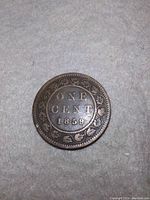 Reverse of the 1859 Canada one cent coin showing denomination and date with decorative maple leaf border.