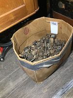 Large cardboard box filled with metal and wooden antique furniture casters showing varied shapes and sizes