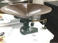 Photo of the full antique BS&M cast iron counter scale showing the round metal basket and sliding brass balance beam on green cast iron base.