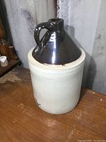 Full view of the 1 gallon stoneware jug showing the beige body and dark brown glazed top and handle.