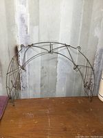 Front view of the metal wireframe wall rack with arch shape and seven hooks visible.