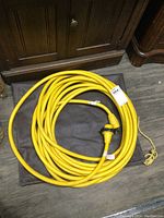 Full view showing the coiled yellow marine power cord and the dark vinyl storage bag beneath it.
