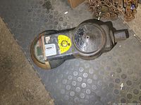 Full view of the parking meter lying on floor showing overall shape and condition.