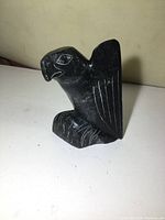 Front side view of black soapstone eagle carving showing detailed engraved wing and beak.