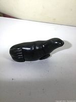 Side view of the black soapstone seal carving showing smooth polished surface and detailed flippers.