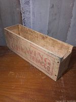 Side view of vintage wooden Stag Chewing Tobacco crate, showing faded red graphics and worn condition.