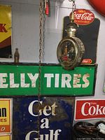 Photo showing the clock hanging in front of vintage signs, highlighting the chain and aged metal case
