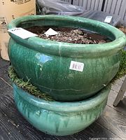 Two stacked green ceramic planter bowls with soil remnants inside, showing size and condition.