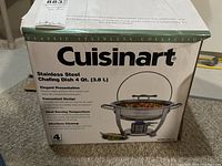Box showing Cuisinart branding, product name, and features: 4 quart (3.8 L) stainless steel chafing dish with elegant presentation, convenient design, ideal serving temperature, and easy cleanup.