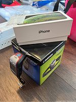 Photo showing an Apple iPhone box stacked on a Garmin Forerunner box with the Garmin wrist device placed on the box.