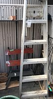 Photo showing the 6ft metal ladder leaning next to the Work Mate folding workbench inside a shed, both weathered with visible staining.