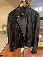 Front view of black Leather Attic leather jacket with quilted shoulder, zippered pockets and diagonal zipper closure.