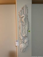 Vertical marine themed wall art piece with seahorse, starfish, sand dollar and shell embellishments in white.