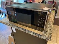 Microwave oven on granite countertop showing overall exterior shape and size.
