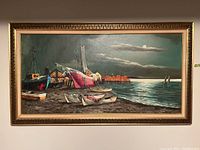 Full view of framed oil painting showing boats at shoreline under moonlit sky