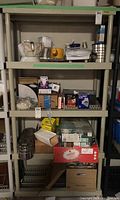 Resin shelf unit filled with assorted household items including appliances, containers, and boxes.