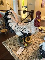 Full view of detailed 14-inch resin rooster figurine painted in white, black, red, and yellow with a sunflower base, placed on granite countertop.