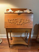 Front view of wood secretary desk with drop-down panel closed, carved decoration, drawer and bottom shelf visible