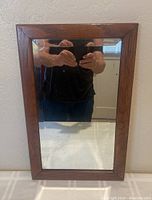 Full front view of antique wooden framed beveled mirror showing glass and frame condition.
