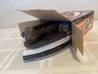 Travel iron partially out of the box showing the white and black iron with power cord wrapped around it.