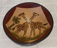 Top view of the wooden bowl showing the hand-painted image of two giraffes and a tree.