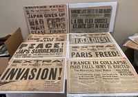 Assorted newspapers laid out, featuring headlines “Japan Gives Up. Cease Firing!”, flier crossing Atlantic, and other WWII-era stories