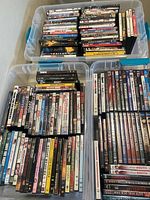 Image showing multiple plastic bins filled with vertically and horizontally stacked DVD cases. Titles from various genres and series are visible.