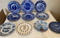 Overview of all 10 historical and presidential collectible plates arranged on surface, showcasing various colors, portraits, and scenes