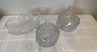 Two lead crystal compotes with lids and one oval lead crystal bowl with floral design on table.