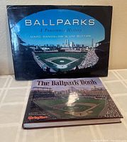 Two books are shown on a table: Ballparks: A Panoramic History (large landscape format) and The Ballpark Book (standard portrait format)