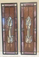 Photo showing both stained glass panels side by side on a light background.
