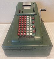 Front angled view of green vintage Victor McKaskey cash register showing numbered keys, crank handle, and display window.