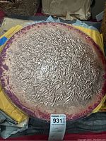 Top view of circular glass Lazy Susan showing textured silver design and pinkish-red border.