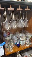 Photos showing a range of glassware hanging and set on shelves including wine glasses, martini glasses, and smaller glasses.