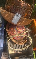 Photo showing an assortment of four baskets including a large shallow one, colorful round basket, and other woven baskets.
