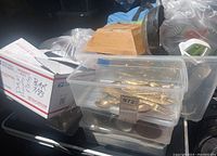 Plastic storage containers with metal flatware and a wooden knife block, some clear glass dishes, and white ceramic serveware items in the background.