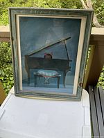 Full view of framed print showing girl with pink bows playing grand piano in teal wood frame with glass.