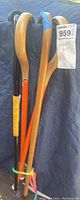 Four walking canes with wooden hooks, three natural wood finish shafts, one bright orange painted shaft, tied together for sale.