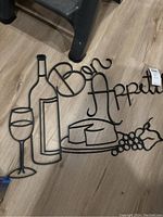 Close-up showing the metal wire art with wine bottle, glass, cheese, grapes, pear and 'Bon Appetit' text