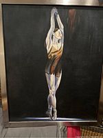 Framed wall art showing a ballerina in a standing pose on a dark background.