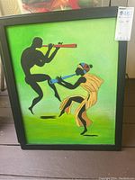 Framed painting of dancer couple with green background, male playing red flute and female with yellow dress and headwrap