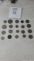 Top-down view of the 20 assorted old coins spread on white background showing different sizes and designs.