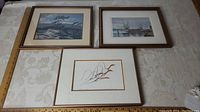 Three framed art prints displayed on a table, showing overall condition and arrangement.