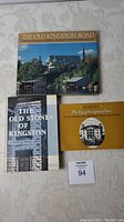 Top view of three Kingston related books on a cloth surface: The Old Kingston Road, The Old Stones of Kingston, The Kingston Connection.
