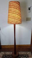 Full height view of the teak floor lamp with woven fabric shade