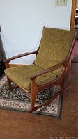 Full profile of teak rocking chair showing frame, rockers and green upholstered cushions